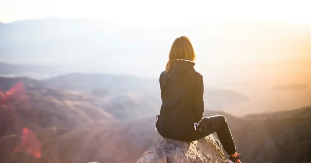A woman on a mountain top overlooking the skyline at sunrise