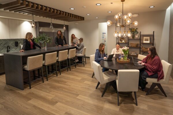 Co-ed kitchen area with staff seating at the island and dining table.