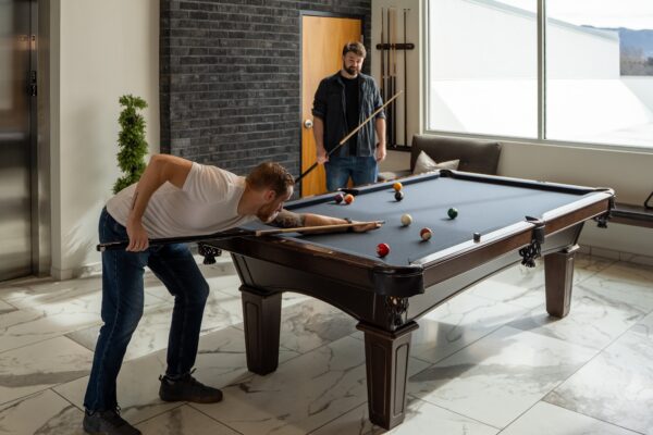 A pool table in the co-ed common area with two men’s residents pictured playing